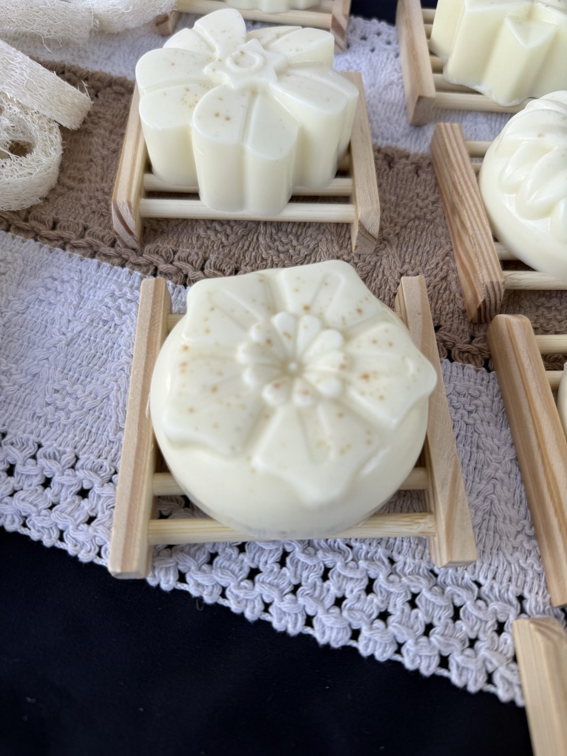 Creamy white floral soaps on wood dishes with loofah slices