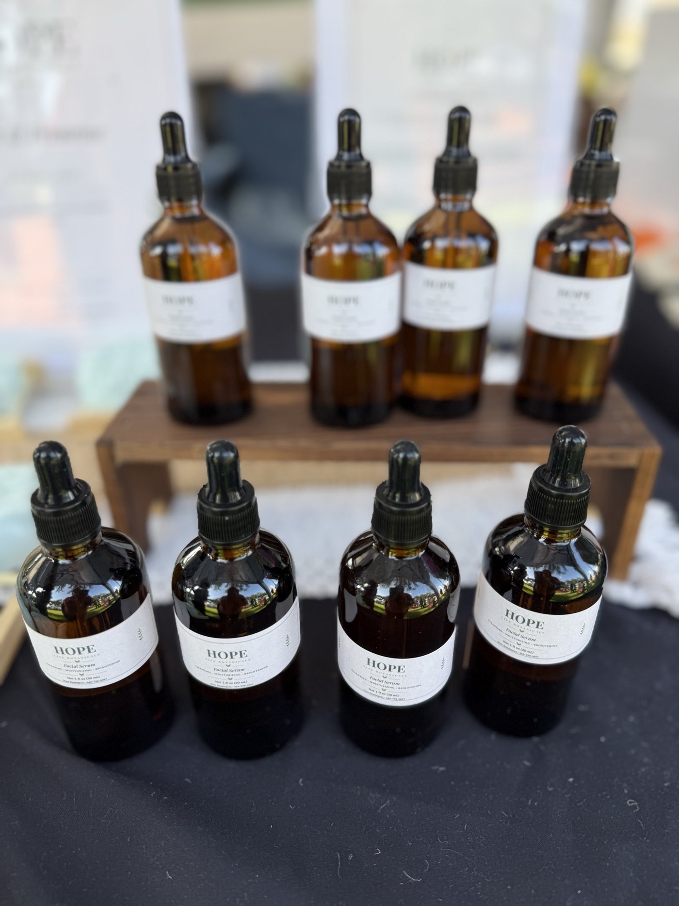 Amber glass dropper bottles of handmade facial serum lined up on a wooden riser